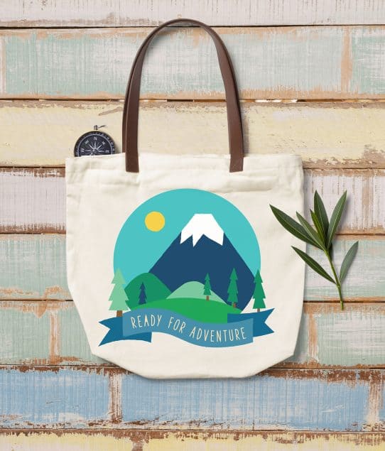 Top view of a white fabric bag with outdoor illustrations on a wooden background.