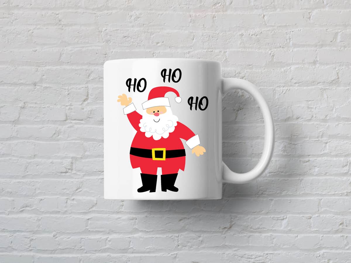 White mug with an illustration of Santa Claus waving his hand and saying "Ho Ho Ho" against a white wall