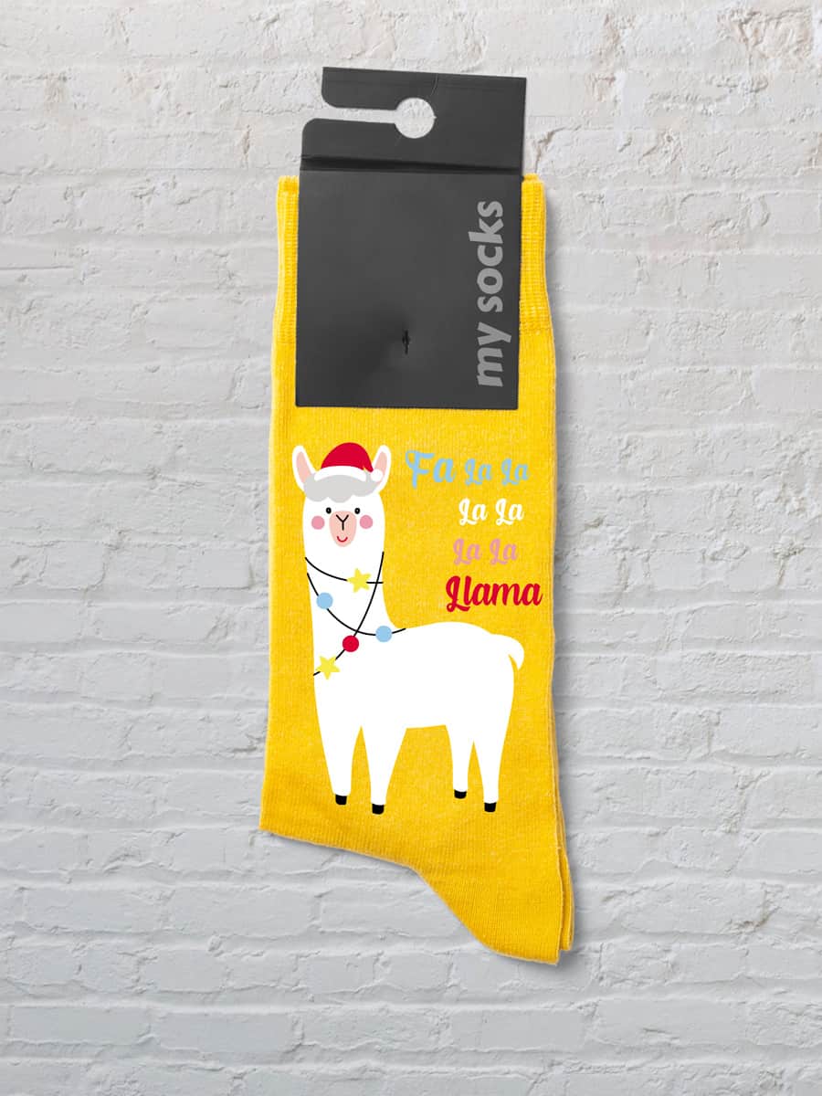 Printed yellow socks featuring a llama wearing a Santa hat and Christmas tinsel against a white wall