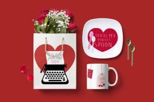 From above, a valentine's day table setting with a paper bag with roses in it, a mug, a plate and two spoons.